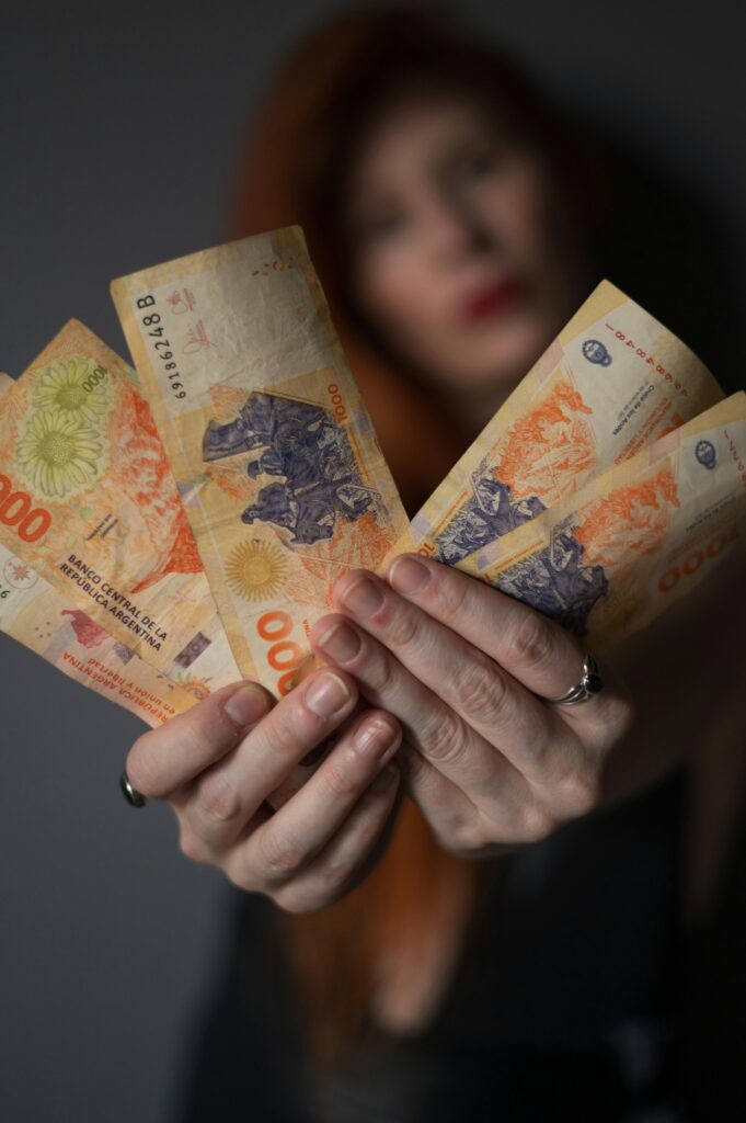 pexels-photo-35878047-35878047 Close-up of a person holding Argentine peso banknotes, showcasing currency details.
